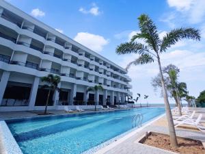 波德申Pacific Regency Beach Resort, Port Dickson的一座拥有游泳池和棕榈树的酒店