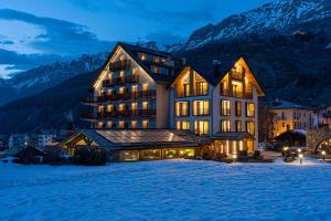 科涅Hotel Sant'Orso - Mountain Lodge & Spa的一座大建筑物,在晚上下雪