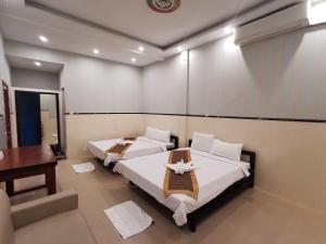 西哈努克Invito Guesthouse的一间卧室配有两张床、一张桌子和一张书桌