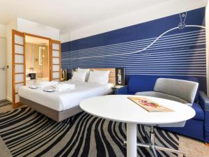 拉罗谢尔拉罗谢尔中心诺富特酒店的酒店客房配有床、桌子和沙发。