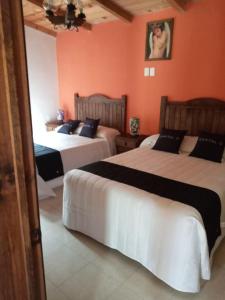Omitlán de JuárezCasa Manning y Salón la Troje By Rotamundos的橙色墙壁客房的两张床