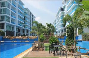华欣My resort HuaHin By U home的大楼旁的游泳池配有桌椅