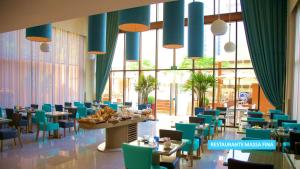 圣保罗Vila Galé Paulista的一间设有蓝色椅子和桌子的用餐室以及窗户。