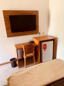 奥兰布拉Parque Hotel Holambra的客房设有书桌、电视和椅子。
