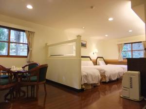 鹿谷乡溪头青年活动中心的酒店客房设有两张床和一张桌子。