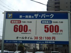 松本松本背包客旅馆的停车场的标志,上面标有价格