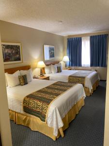 诺曼Thunderbird Lodge, Norman, OK的两张位于酒店客房的床,配有蓝色窗帘