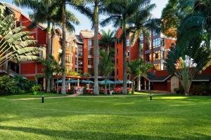 阿鲁沙Kibo Palace Hotel Arusha的一座大型红色建筑,在公园里种有棕榈树