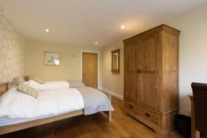 拉科克Clubhouse Cottage的一间带两张床和大型木制橱柜的卧室