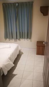邦咯Pangkor staycation apartment的一间卧室配有床和蓝色窗帘