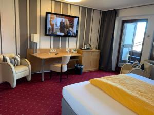 巴特拉斯费Hotel Pension Berghaus Sieben的酒店客房设有一张桌子和一台墙上的电视。