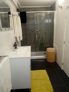 曼瓜尔迪Casa do soito的浴室设有水槽和黄色地毯的淋浴。
