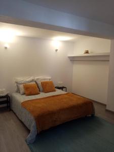 曼瓜尔迪Casa do soito的一间卧室配有一张大床和两个橙色枕头