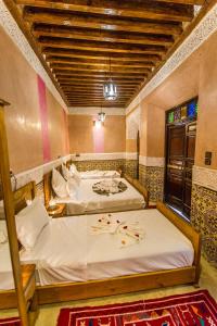 马拉喀什Riad Atlas Mejbar的一间卧室设有两张带白色床单的床和窗户。