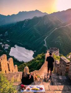北京北京遇花园休闲度假民宿的坐在墙边,看着山谷的男人和女人