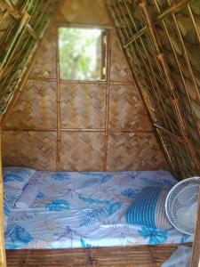 TalipanDupas Luce Love Lodges的茅草客房的一张床位,设有窗户