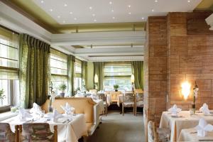 拜尔斯布龙奥登霍夫费伦酒店的餐厅设有白色的桌椅和窗户。