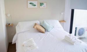 科尔多瓦Guemes Apart Nueva Cordoba的白色的床,配有白色床单和蓝色枕头