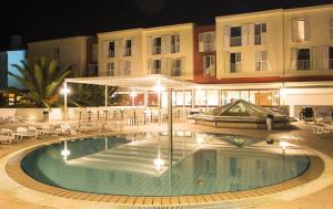 科尔丘拉Marko Polo Hotel by Aminess的一座游泳池,在晚上在建筑物前