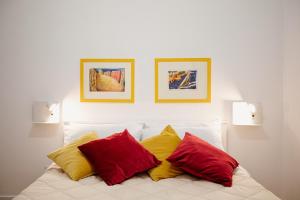 锡拉库扎Les Amis的一张白色的床,上面有三个红色和黄色的枕头