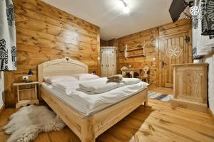 黑杜纳耶茨Agroturystyka "Na Borowej"的卧室配有一张床铺,位于带木墙的房间内