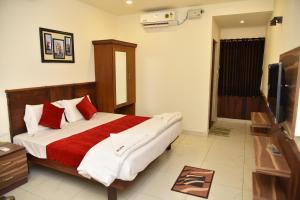 帕拉尼Sree Ganesh Inn的一间卧室配有一张带红色和白色枕头的大床