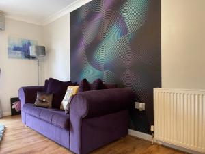 马瑟韦尔King Court Apartment的客厅里设有一张紫色长沙发,客厅里设有一面墙