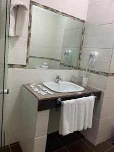 埃斯特角城Punta del Este Shelton Hotel的浴室配有盥洗盆、镜子和毛巾