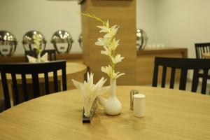 西里古里VIPs Hotel Olive的一张木桌,上面有花卉花瓶