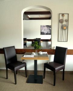 蒂罗尔-基希贝格基希贝格公园酒店的一张桌子和两把椅子,位于一个带镜子的房间