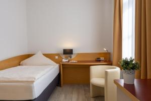 开姆尼茨阿尔特穆尔酒店的配有一张床和一张书桌的酒店客房