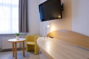 开姆尼茨阿尔特穆尔酒店的酒店客房设有一张桌子,墙上配有电视。