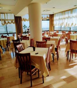里米尼城堡酒店的餐厅设有白色的桌椅和窗户。