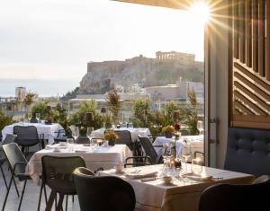 雅典雅典伊莱克特拉酒店的餐厅设有桌椅,享有雅典卫城的景色