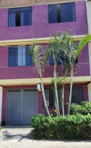 利马EL TUMI - Aeropuerto的一座紫色的建筑,前面有两棵棕榈树