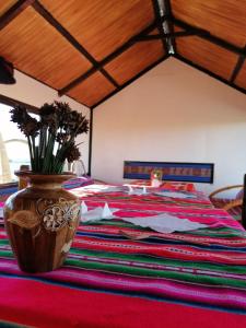 普诺Uros Lake Titicaca Lodge的一间卧室,配有一张带花瓶的床