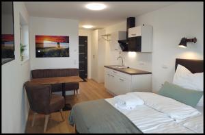 NidderauFernweg Apartments的一间卧室配有一张床铺和一张桌子,还设有一间厨房
