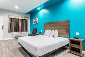 金伍德Americas Best Value Inn & Suites Kingwood IAH Airport的一间卧室设有一张大床和蓝色的墙壁