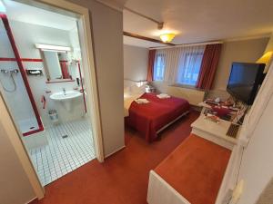 奎德林堡Hotel Zur Goldenen Sonne的酒店客房设有红色的床和浴室。