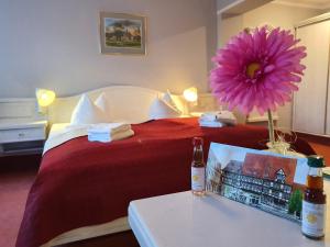 奎德林堡Hotel Zur Goldenen Sonne的一间酒店客房,配有一张红色的床,桌子上放着鲜花