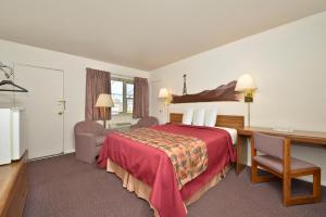 北普拉特美洲最佳价值旅馆北普拉特的红色的床、书桌和书桌。