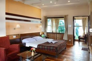 大吉岭Darjeeling Tourist Lodge的一间卧室配有一张床、一张沙发和一把椅子
