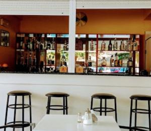 马塔拉Hotel Orama-Matala的酒吧,带两张桌子和三把酒吧凳