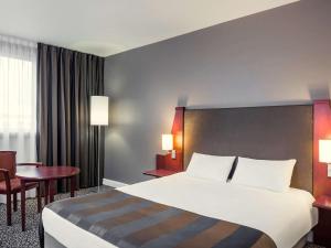 丰特奈苏布瓦巴黎巴尔德特奈美居酒店的酒店客房设有一张大床和一张桌子。