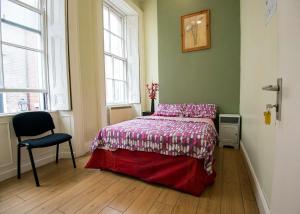 都柏林阿帕切青年旅社的一间卧室配有一张床和一把椅子,还有两个窗户