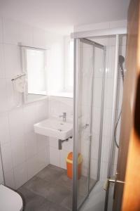 韦斯巴德贝尔韦达雷餐厅酒店的白色的浴室设有水槽和淋浴。