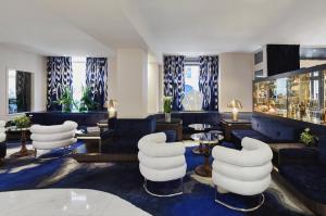 巴黎贝尔阿米酒店的酒店大堂设有白色的椅子和桌子。