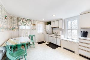 楠塔基特The Rose Cottage的厨房配有白色橱柜和桌椅