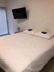 悉尼Bondi Beach Studios Suite的卧室配有白色的床和平面电视。