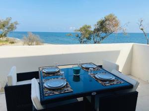 林古泽塔Résidence Marina Di Bravone的一张蓝色桌子,桌子上摆放着椅子和盘子,还有大海